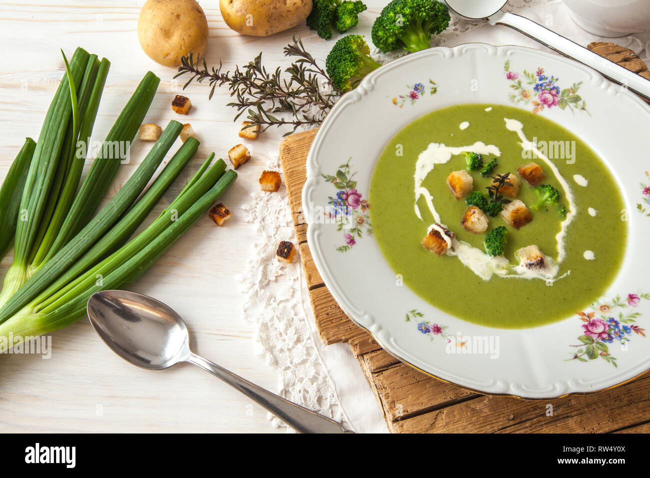 Frühling detox Brokkoli green Creme Suppe mit Kartoffeln und vegane Sahne in Schüssel auf hellen Holz- Platine mit weißem Hintergrund, Ansicht von oben. Sauber, Essen Stockfoto