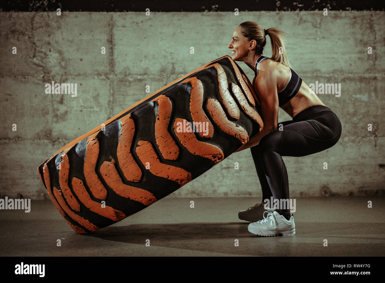 Junge muskulöse Frau spiegeln ein Rad Reifen auf Training im Fitnessstudio. Stockfoto
