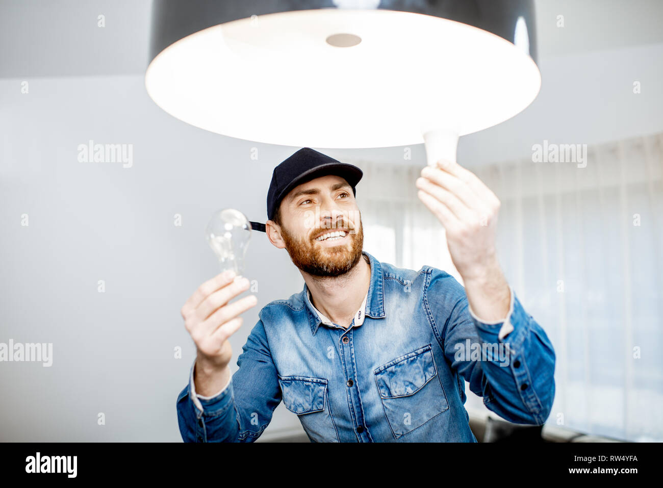 Heimwerker die Wahl zwischen Energie sparen und billig Glühlampe während wechselnde Licht im Appartement Stockfoto