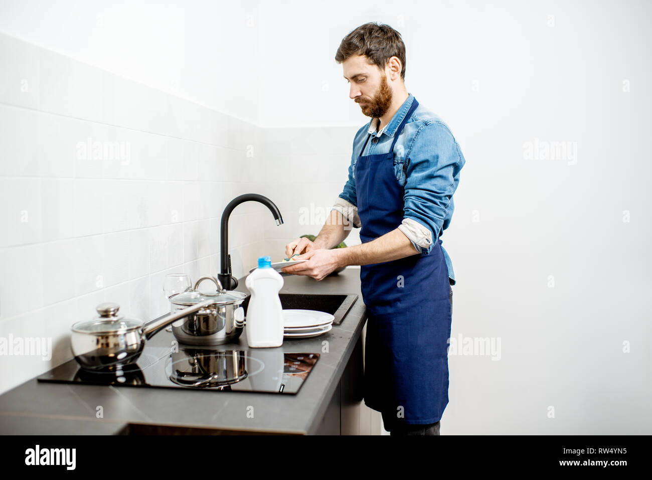 Schöner Mann im Vorfeld tun, Haushalt Geschirr in der Küche zu Hause. Stockfoto