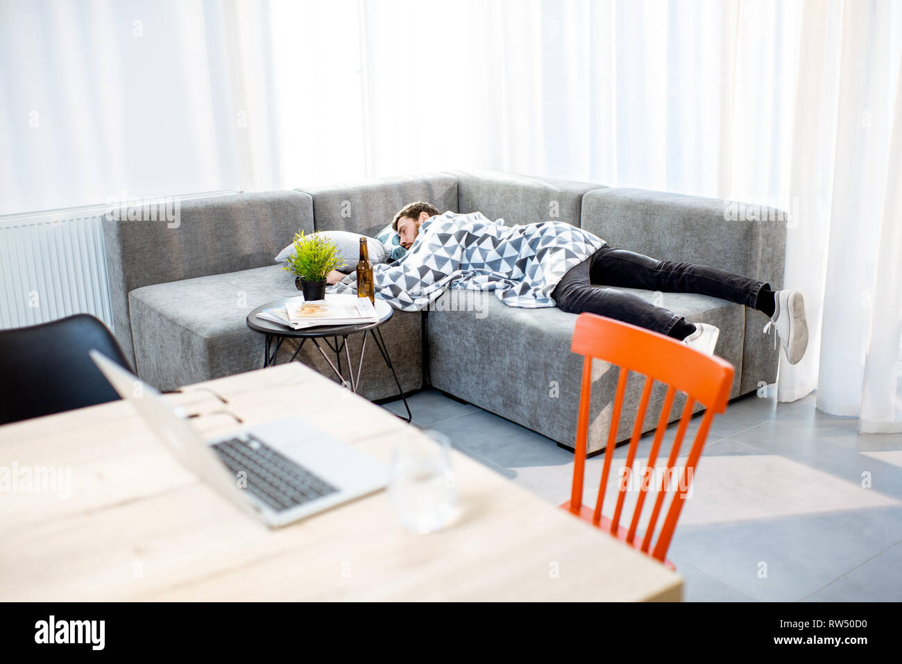 Betrunkener Mann auf der Couch liegen mit Decke, leiden unter dem Alkoholismus zu Hause Stockfoto