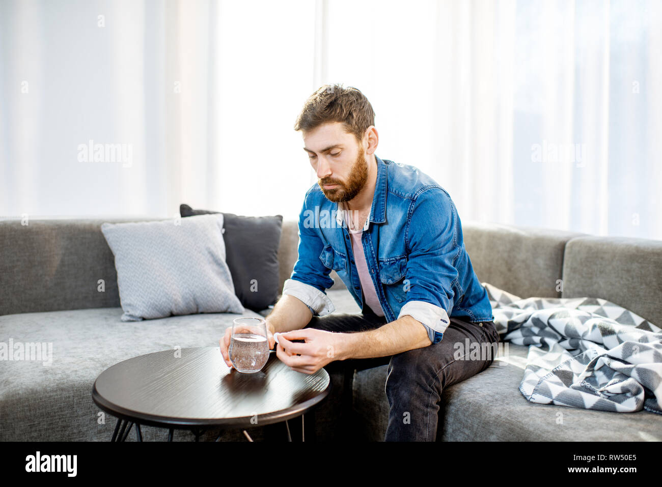 Mann trinken einige Arzneimittel schlechte Gefühl oder Kater nach der Alkohol Partei, sitzen auf der Couch zu Hause Stockfoto