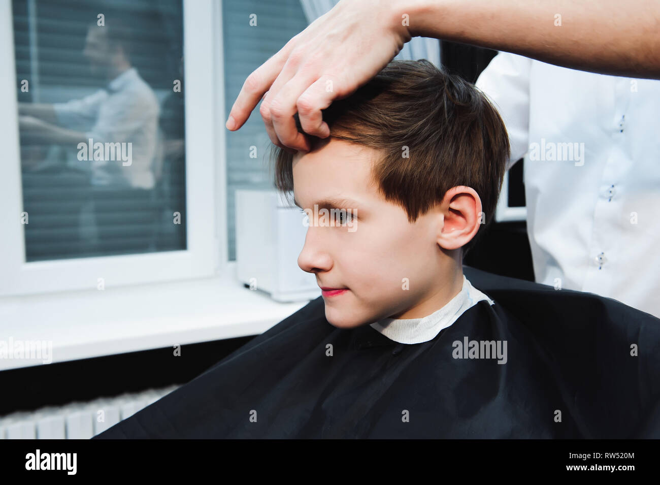 Junge schöne Friseur die Haare schneiden von süßen Jungen im barbershop Stockfoto