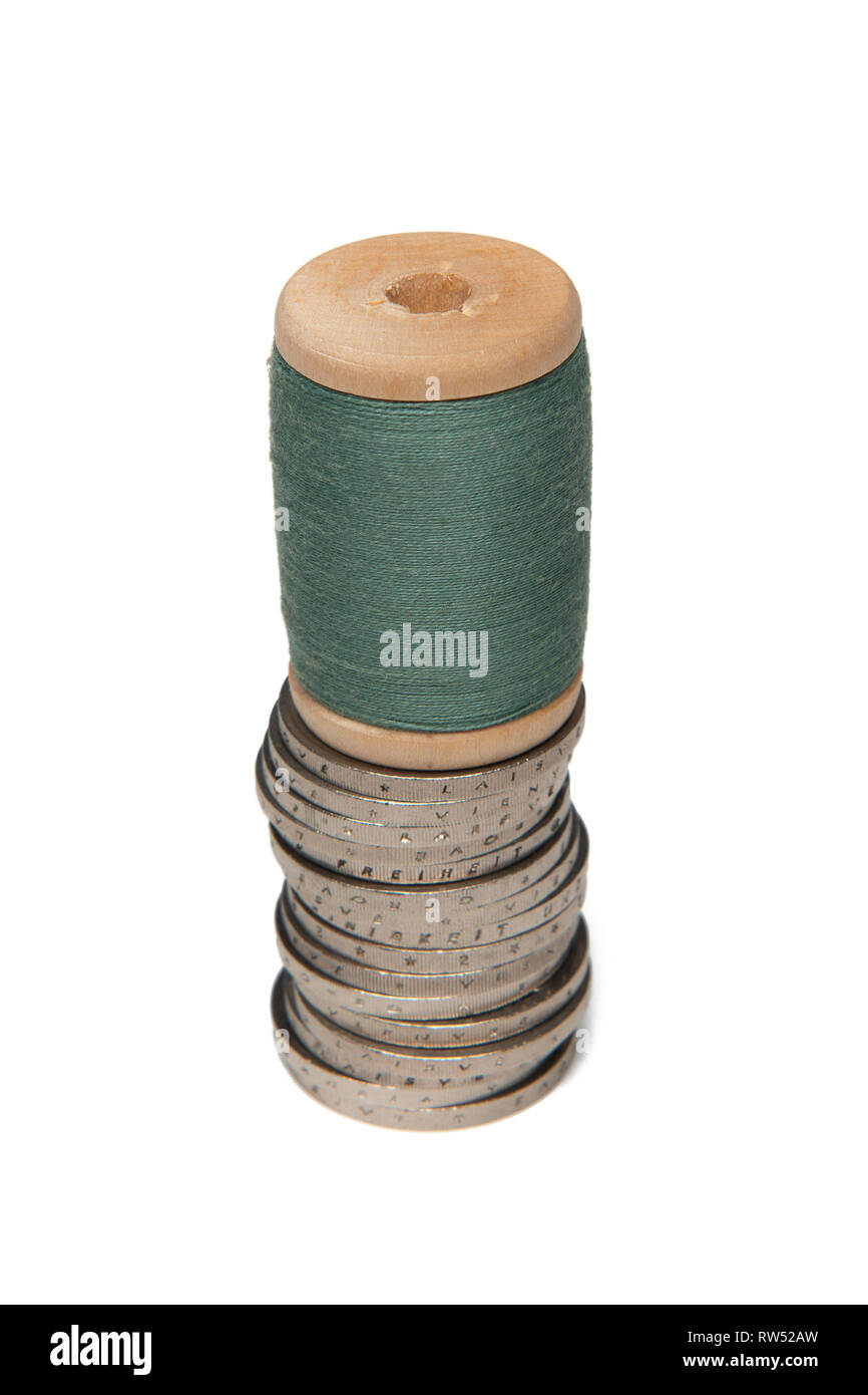 Reihen von Münzen auf weißem Hintergrund neben bunten Thread auf hölzernen Schieber Stockfoto