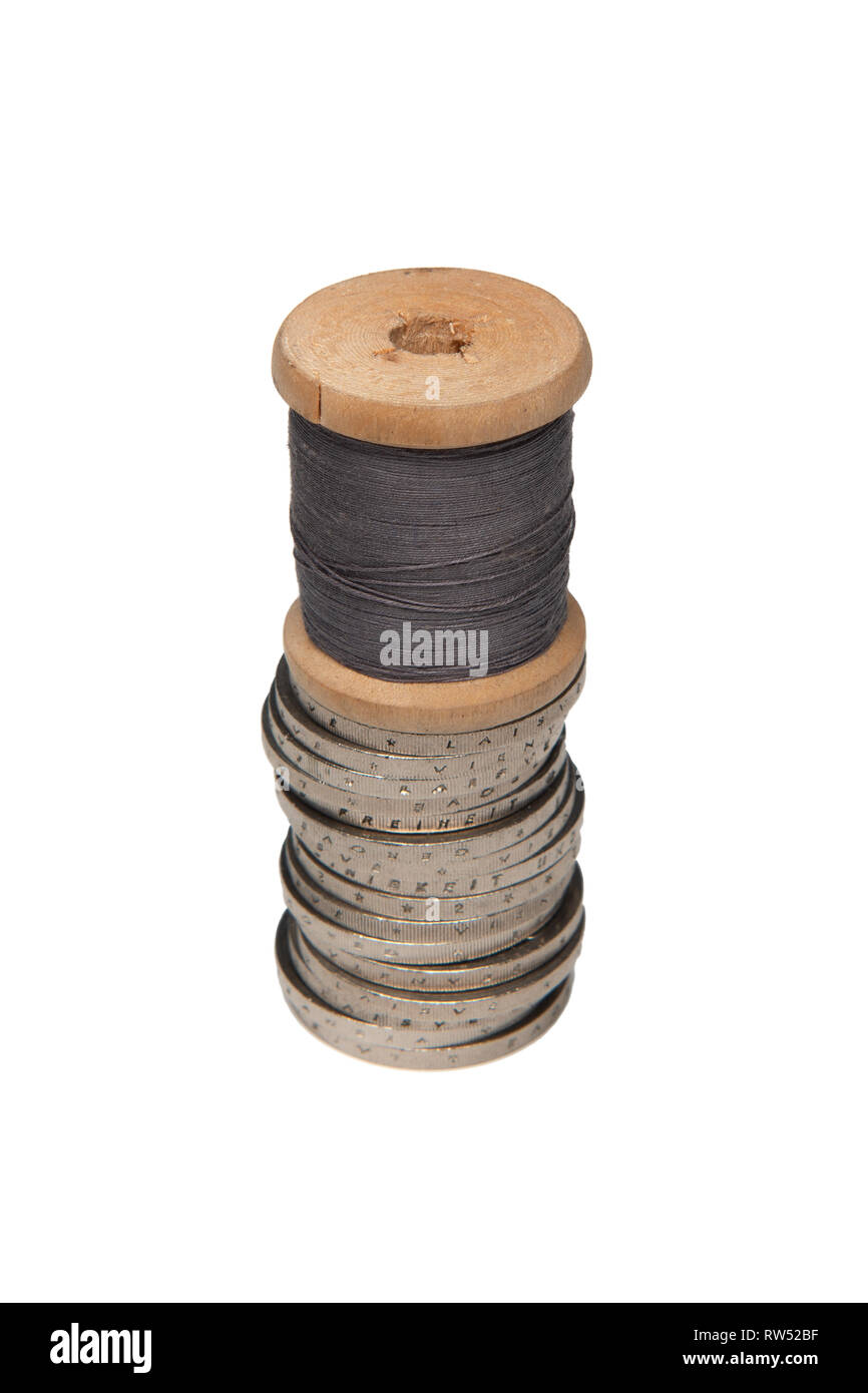 Reihen von Münzen auf weißem Hintergrund neben bunten Thread auf hölzernen Schieber Stockfoto