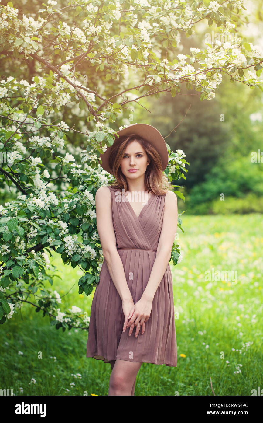 Junge perfekte Frau mit braunen schulterlangen Haare Haarschnitt. Schönes Modell Mädchen im Sommerkleid und fedora Hut auf Blumen Hintergrund Stockfoto