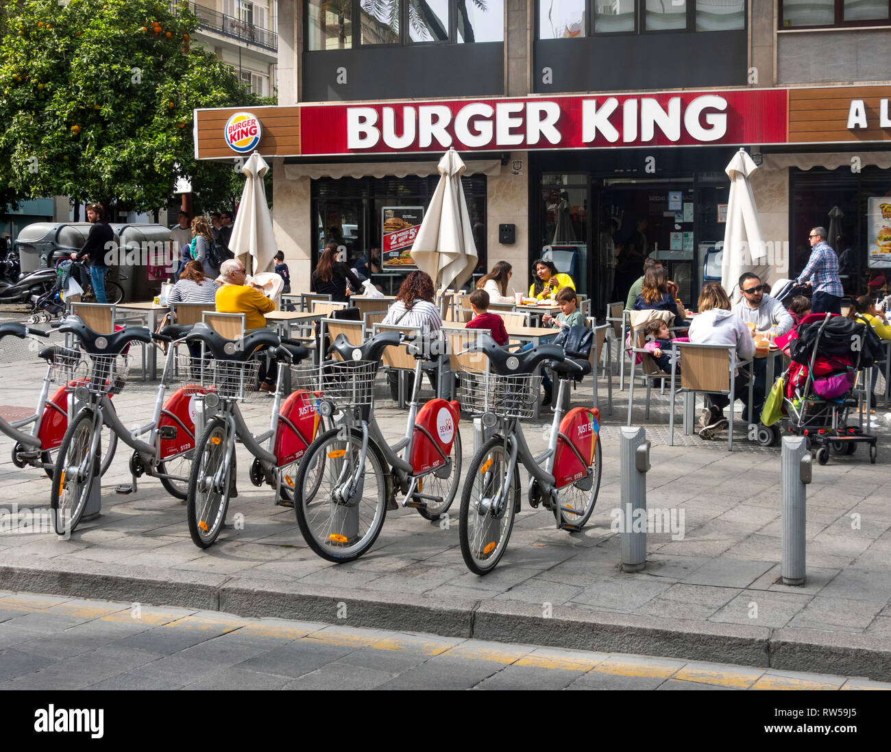 Kunden, die die Sonne im Freien vor einem Burger King in Sevilla, Spanien, genießen Stockfoto