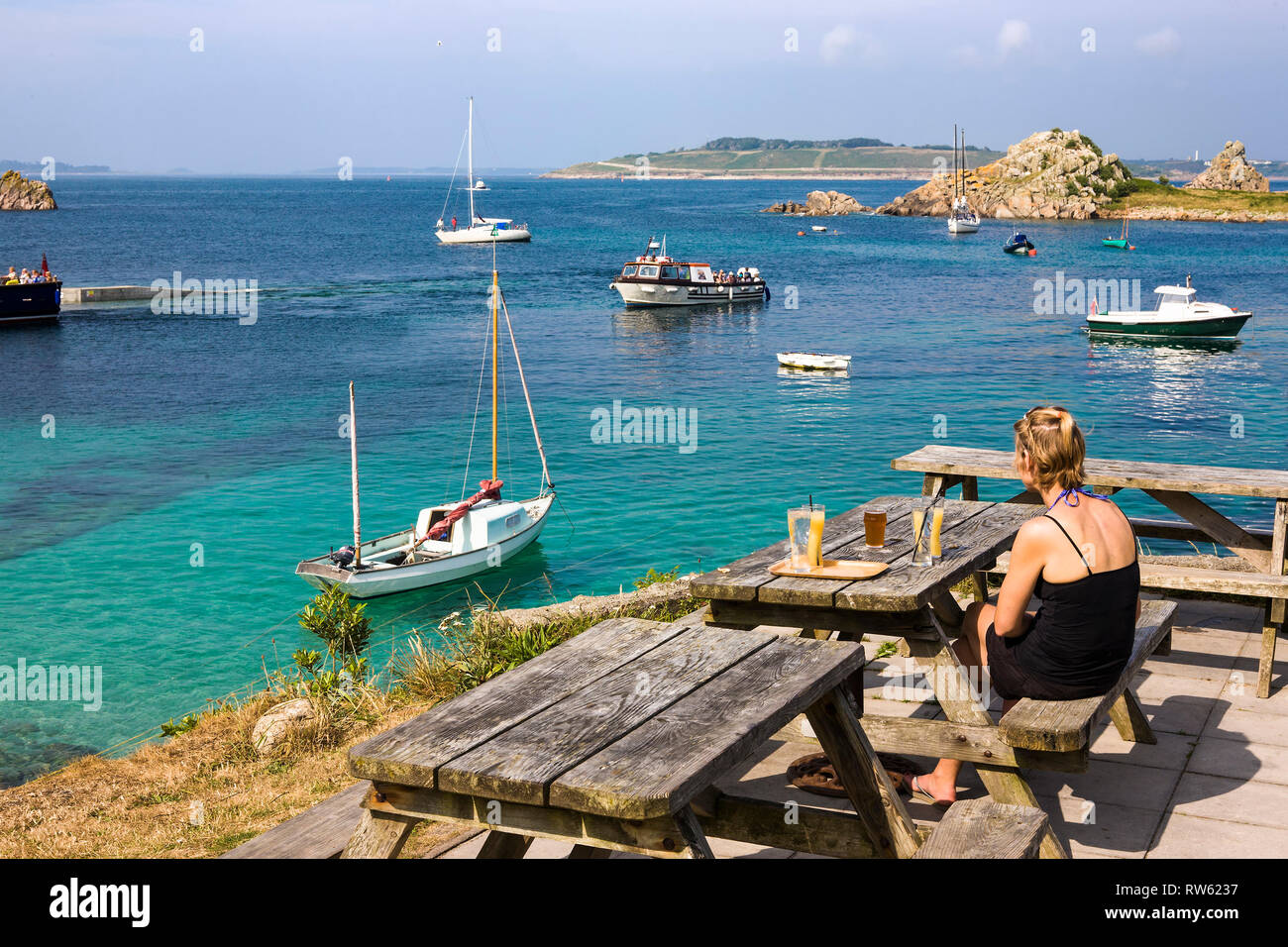 Das Sitzen auf der Terrasse des Kopfes des Turk, mit Blick auf Porth Conger und der Insel Gugh, St. Agnes, Isles of Scilly, Großbritannien Stockfoto