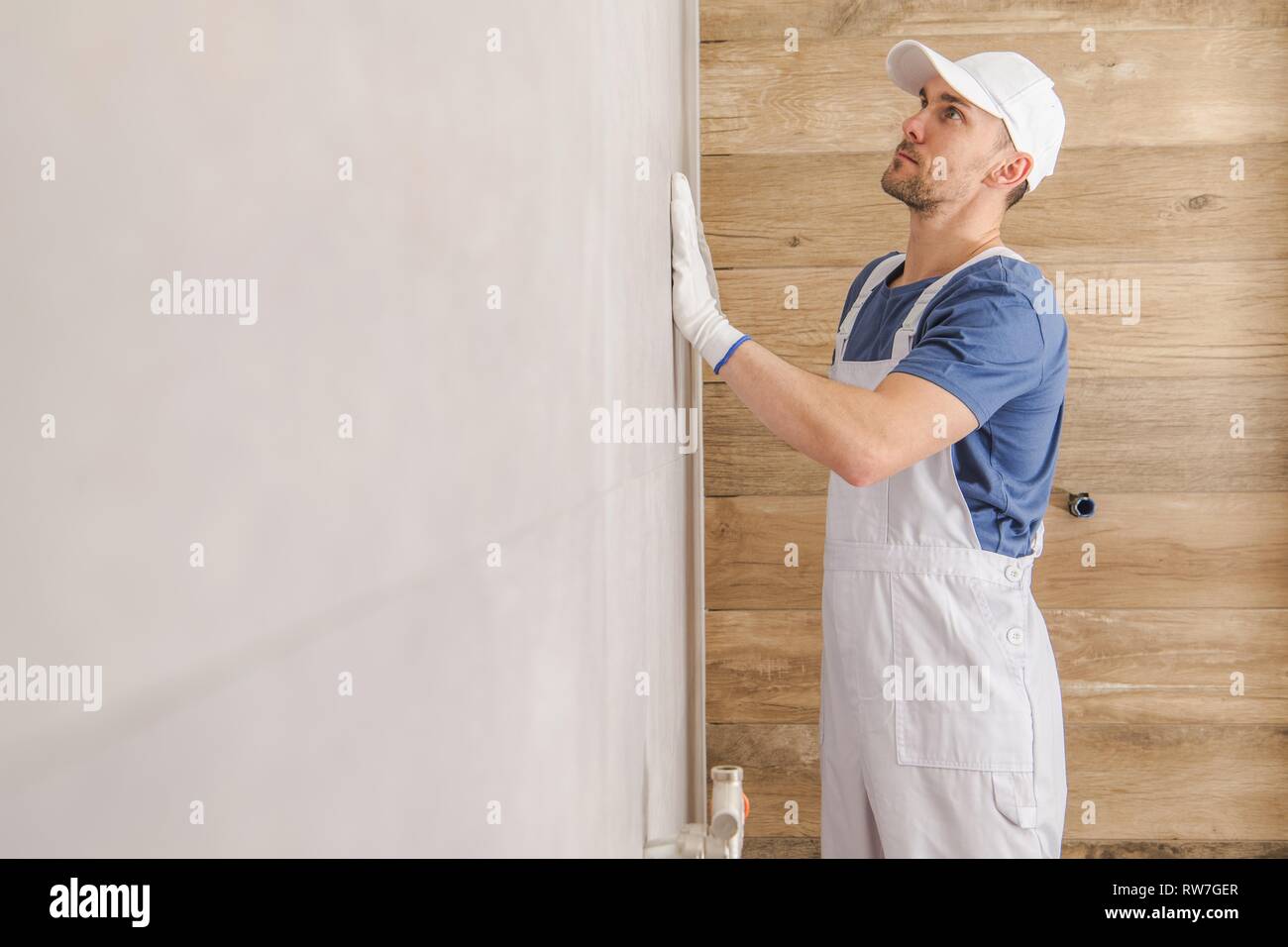 Keramische Fliesen Wand Endbearbeitung. Kaukasische Fliesen Installer Kontrolle auf der fertigen Wand im Badezimmer. Stockfoto