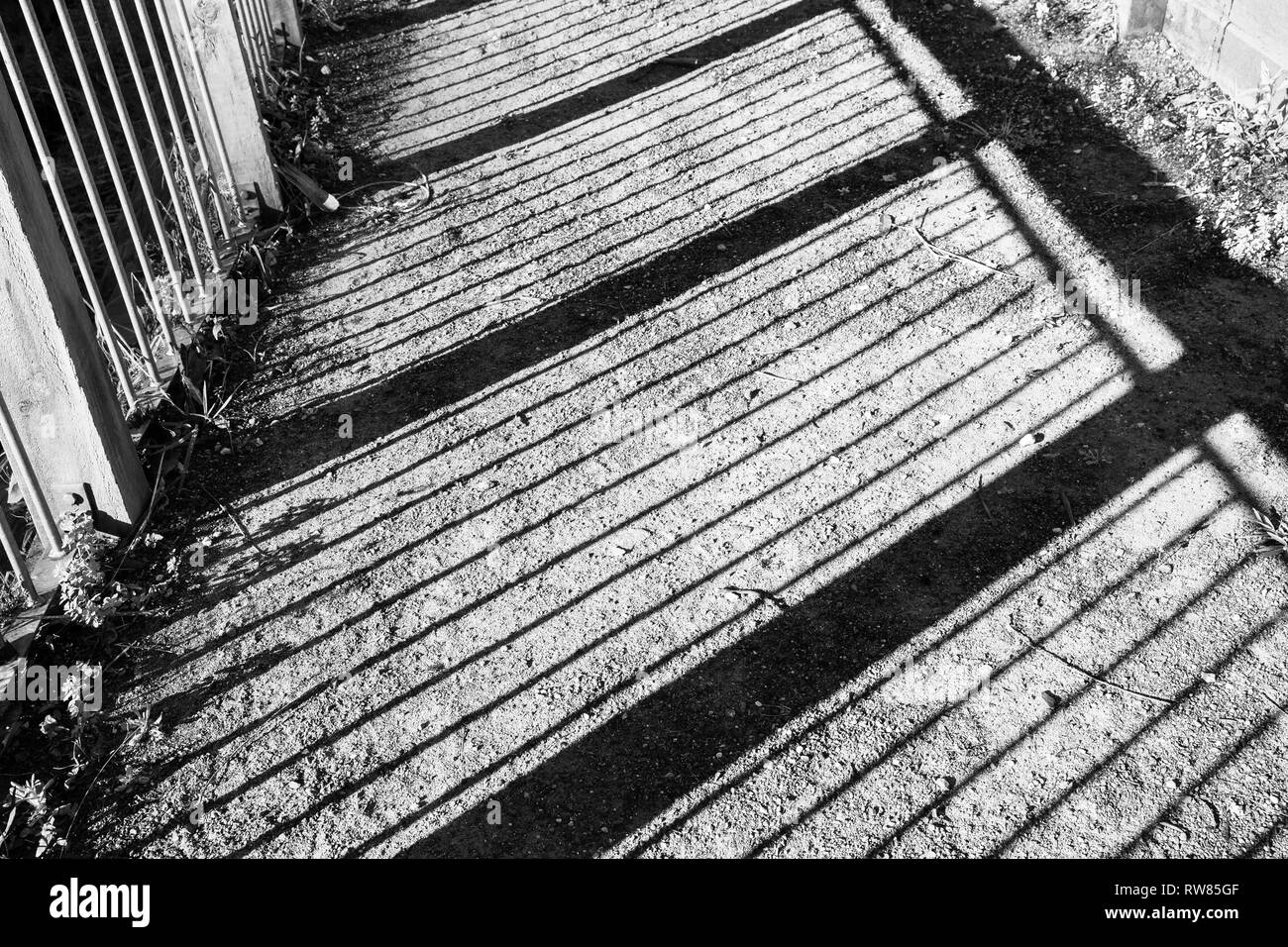 Interessante Perspektive auf Schatten von einem Zaun gegen einen Kies Boden gut gemacht. Stockfoto