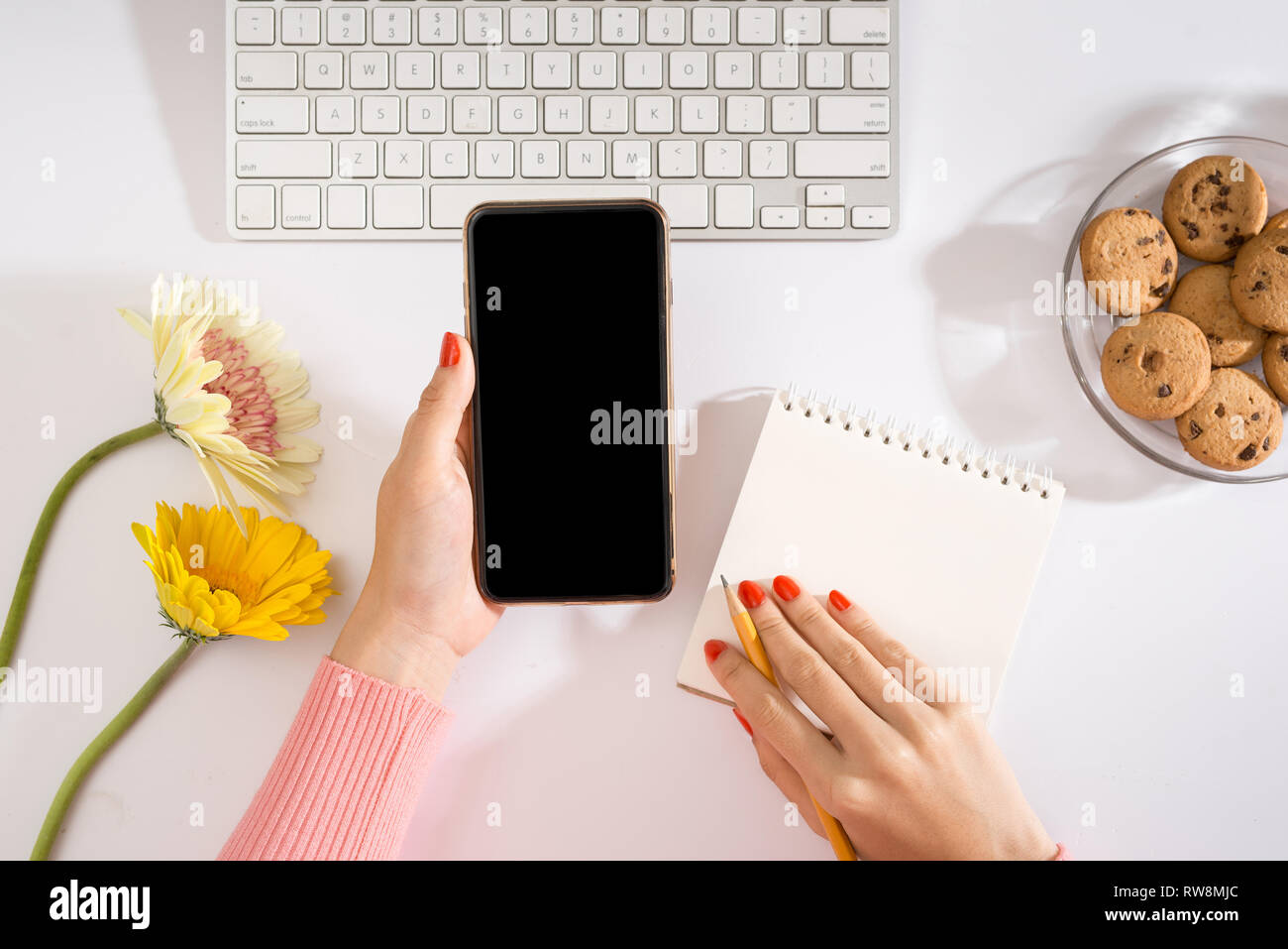 Hände eine Geschäftsfrau auf einer Computertastatur tippen und Telefon in der anderen Hand hält Stockfoto