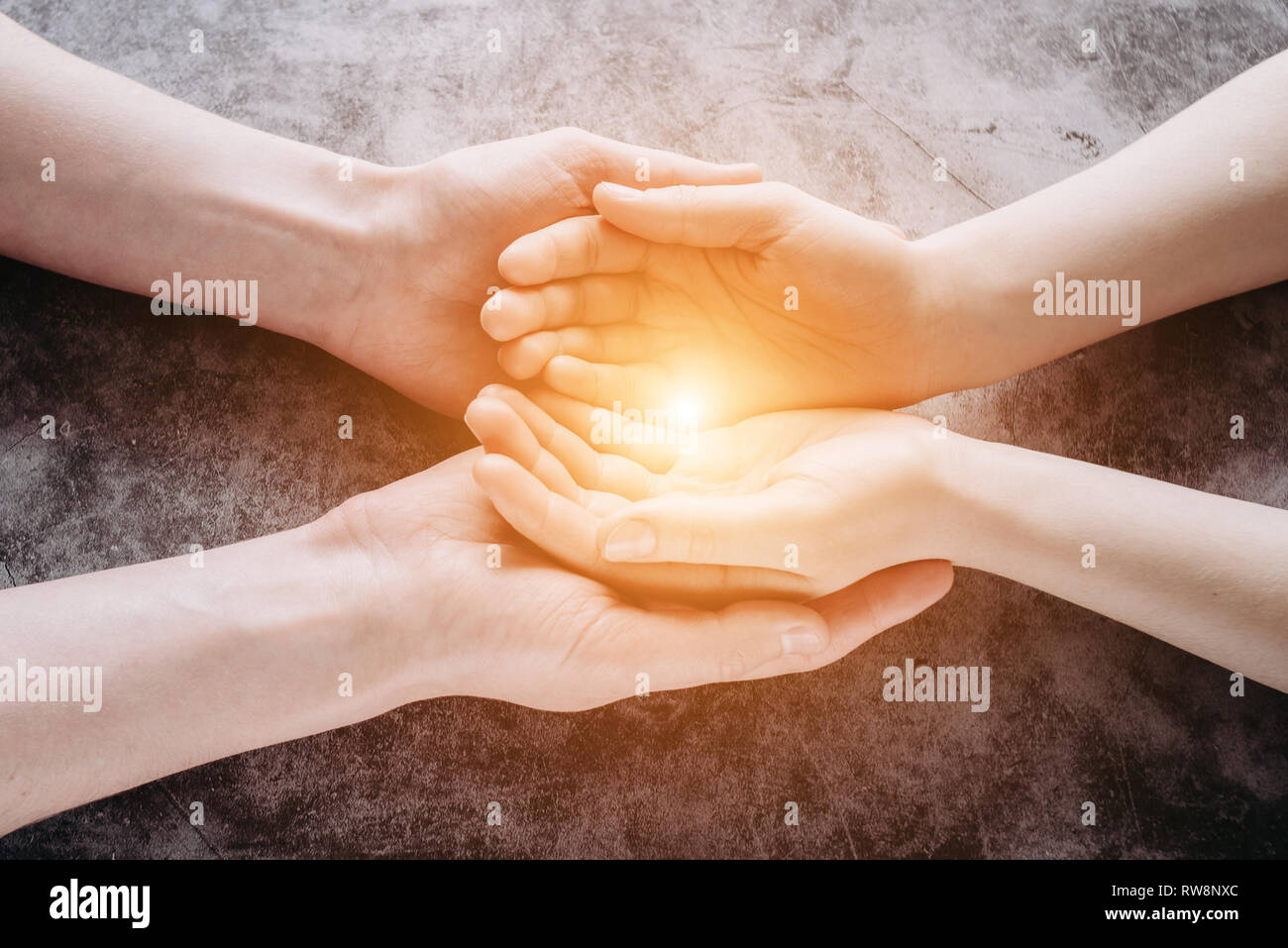 Licht in der jungen Familie Hände mit Hilfe, Schutz und Unterstützung Symbol. Gemeinsame Hoffnung Konzept Stockfoto