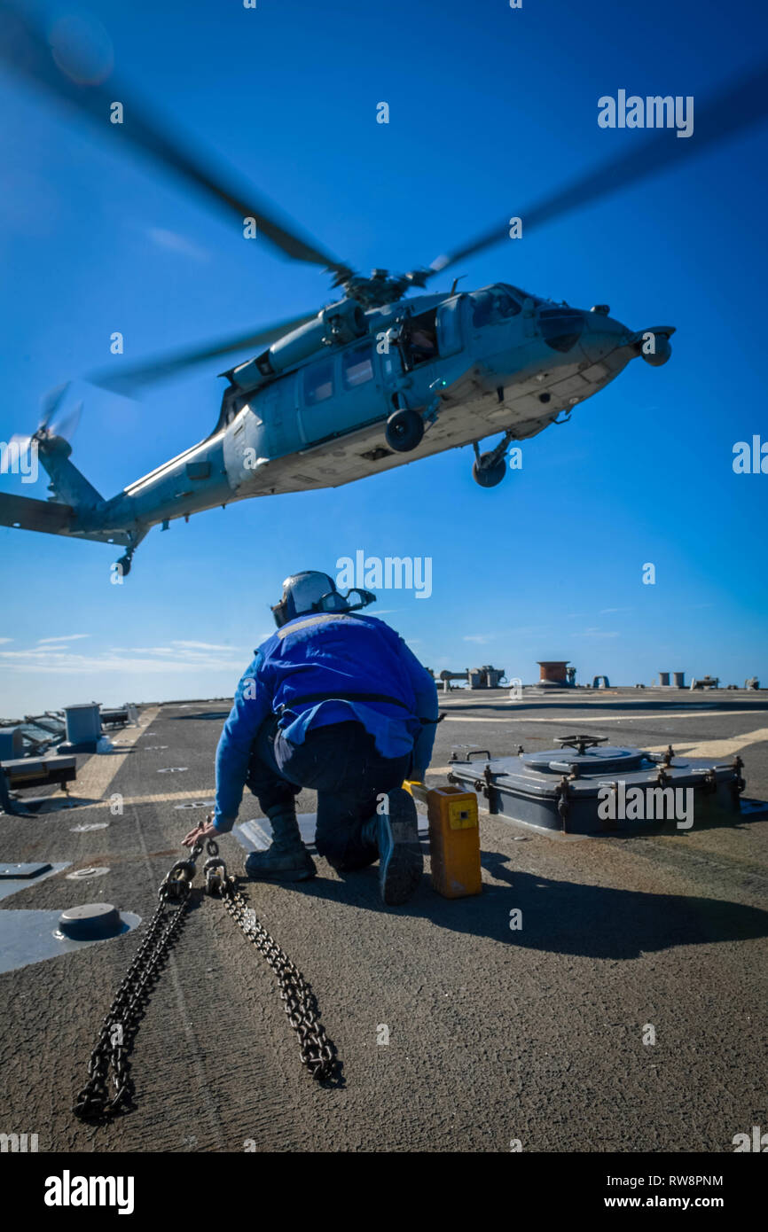 ARABIAN GULF (Mar. 1, 2019) Bootsmann Mate Seemann Jackson Perkins bereitet mit Keilen und Ketten ein MH-60S Sea Hawk Hubschrauber an die "Ladegeräte" der Hubschrauber Meer Combat Squadron (HSC) 26 Landung an Bord der Arleigh-Burke-Klasse geführte Anti-raketen-Zerstörer USS Mitscher (DDG57). Mitscher ist in die USA 5 Flotte Bereich der Maßnahmen zur Unterstützung der Marine im Einsatz für die Stabilität und Sicherheit in der Region zu gewährleisten und verbindet das Mittelmeer und den Pazifischen Raum durch den westlichen Indischen Ozean und drei strategischen Punkten ersticken. (U.S. Marine Foto von Massenkommunikation Speciali Stockfoto