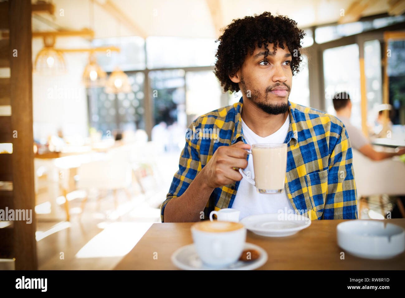 Starten von neuen Tag im Cafe. Seitenansicht des jungen afrikanischen Mann hält Kaffee Tasse ein Stockfoto