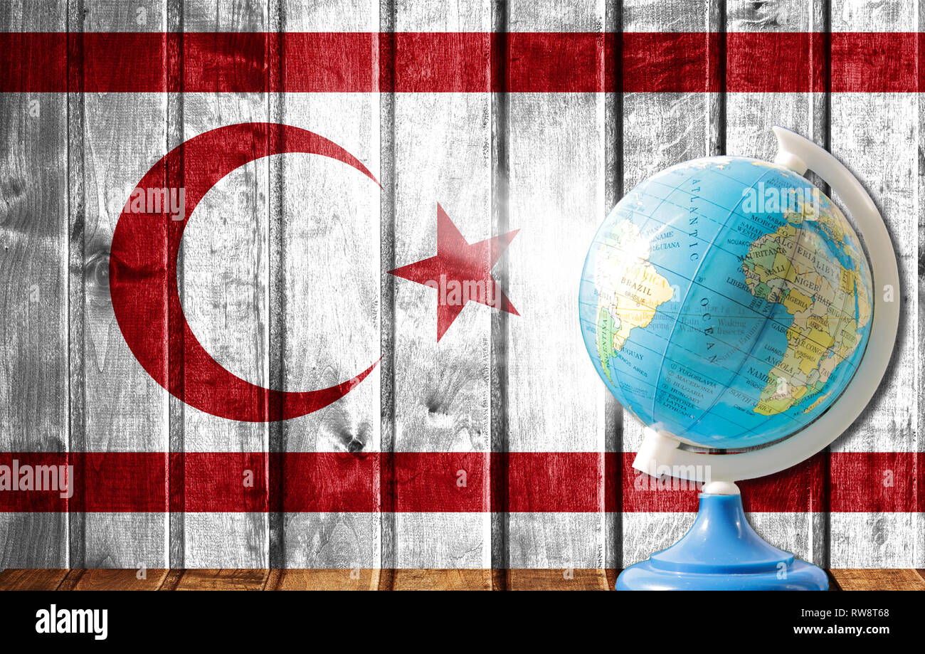 Globus mit einer Weltkarte auf einem hölzernen Hintergrund mit dem Bild der Flagge der Türkischen Republik Nordzypern. Das Konzept der Reisen und Freizeit abr Stockfoto