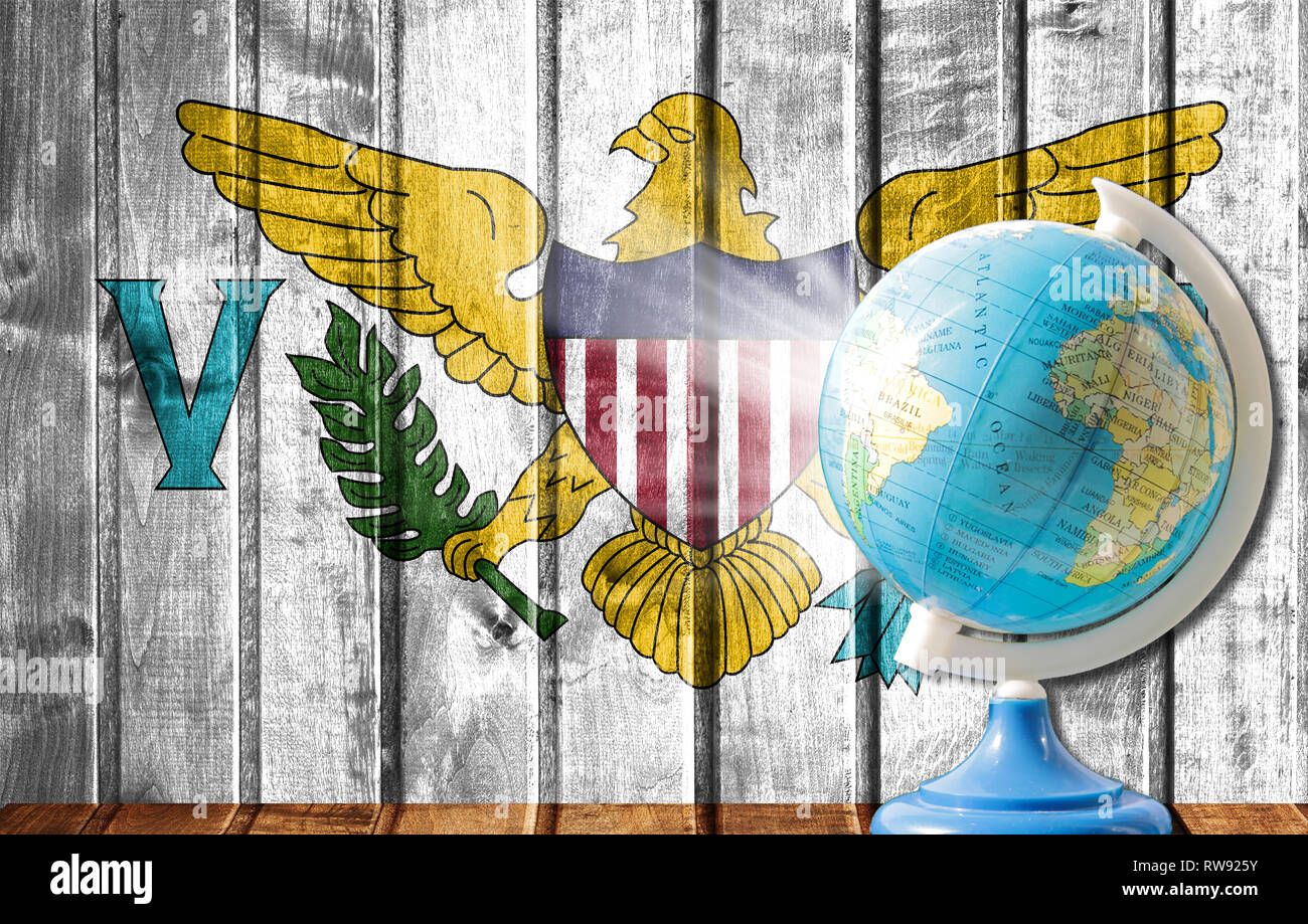 Globus mit einer Weltkarte auf einem hölzernen Hintergrund mit dem Bild der Flagge Virgin Islands der Vereinigten Staaten. Das Konzept der Reisen und Freizeit abr Stockfoto