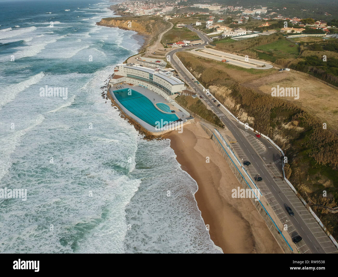 Luftaufnahme von einem großen Sandstrand mit Wellen und einem großen Ocean Pool. Portugiesische Küste Stockfoto