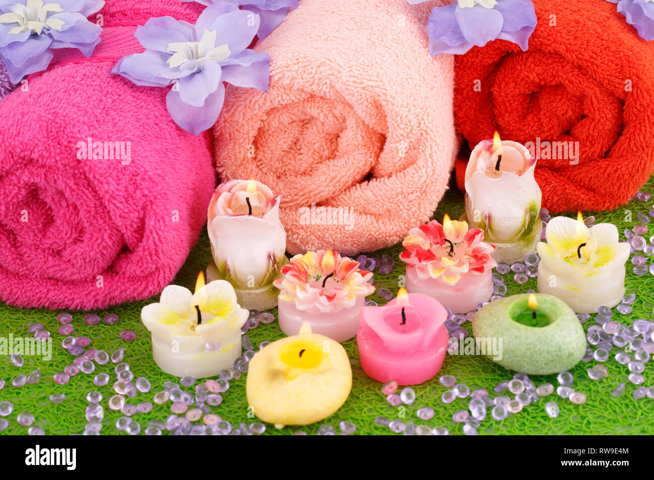 Bad mit Handtüchern, Kerzen und Blumen auf Kunststoff-Hintergrund festlegen. Stockfoto