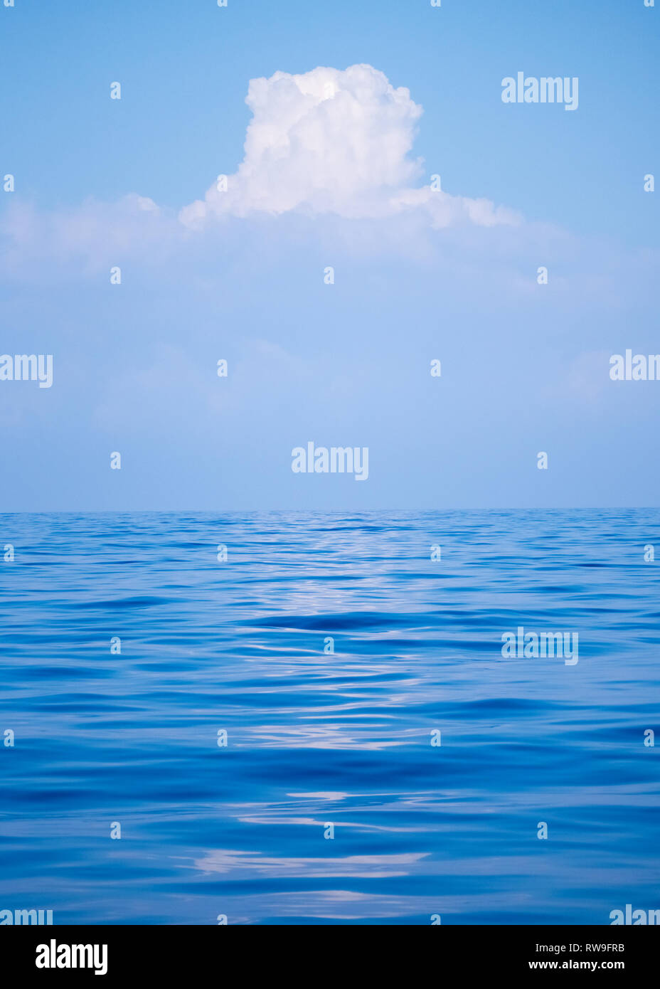 Ein bauchiger Cumulus weiße Wolke Bildung in einem blauen Himmel über einer ruhigen Wellen plätschern ruhig leer mit niemand Mittelmeer Stockfoto