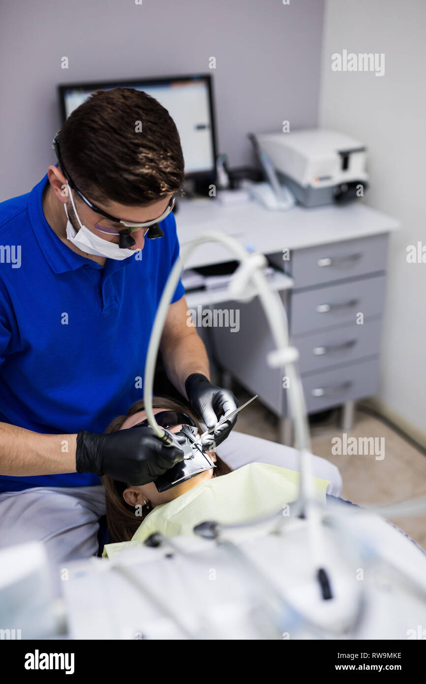 Mann an Zahnarzt Klinik erhält der zahnmedizinischen Behandlung ein Loch in einen Zahn zu füllen. Zahnersatz und Verbundmaterial Polymerisation Behandlung der Zähne. Stockfoto