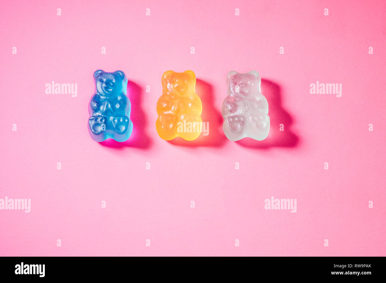 Eine Nahaufnahme von drei bunten Gummibärchen, auf einem rosa Hintergrund mit Mohn studio Licht fotografiert. Stockfoto