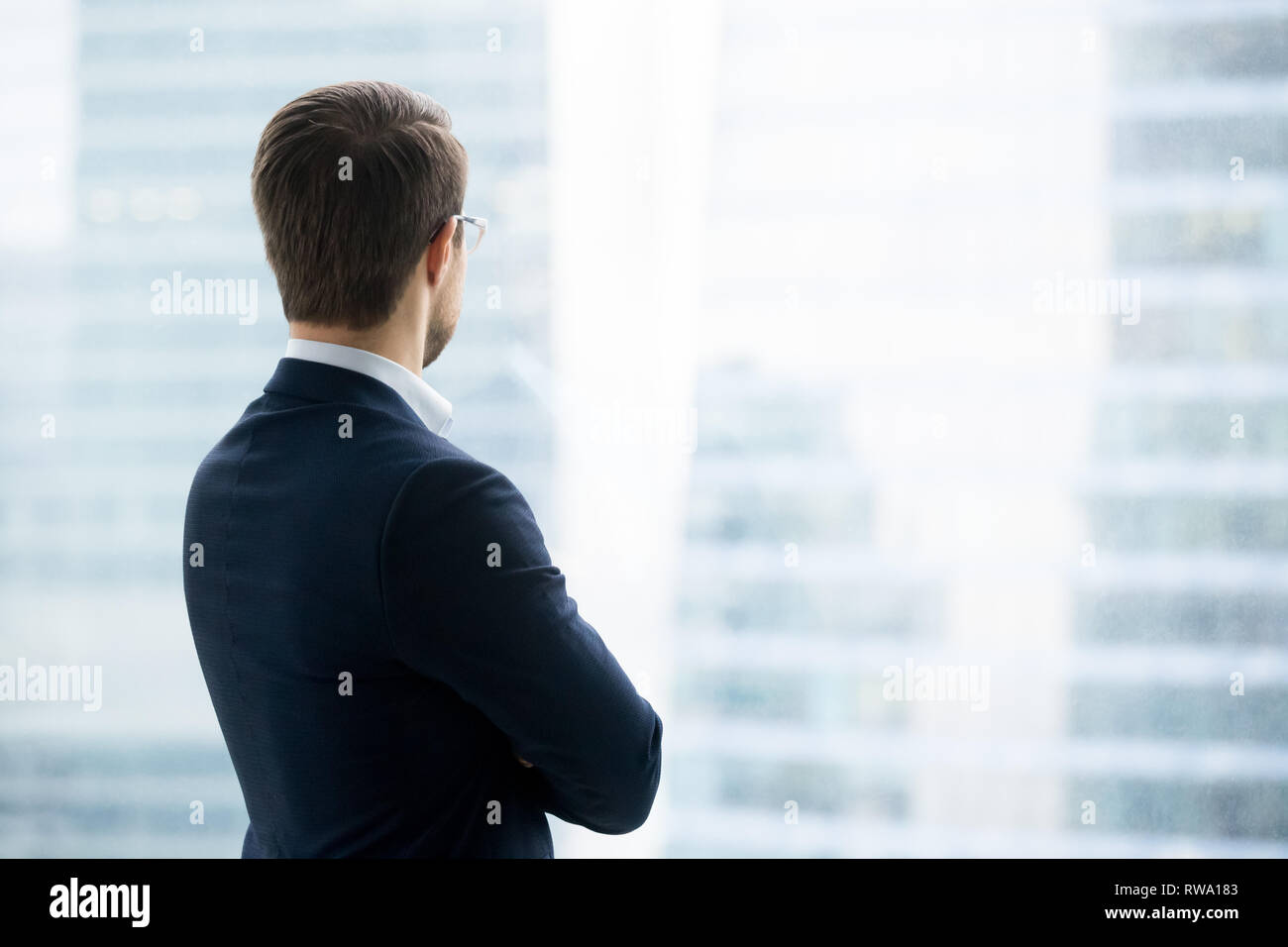 Ansicht der Rückseite des Geschäftsmann in Anzug ständigen Blick durch Fenster Stockfoto