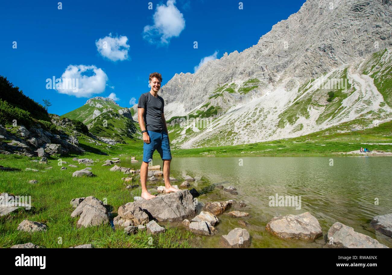 Junge Mann steht auf Stein, Berg See am Prinz-Luitpold-Haus, Allgäuer Alpen, Bad Hindelang, Allgäu, Bayern, Deutschland Stockfoto