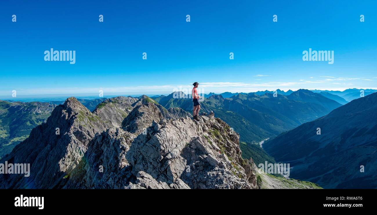 Wanderer steht auf Felsen in die Ferne suchen, Wanderweg am Hochvogel, Blick vom Sattel auf der Kreuzspitze auf Stockfoto