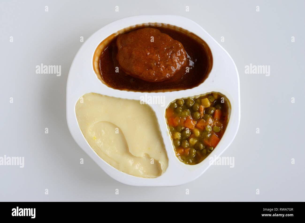 Zubereitete Mahlzeit mit Fleisch, Frikadellen, Kartoffelbrei, Erbsen und Karotten in Kunststoffplatten, Deutschland Stockfoto