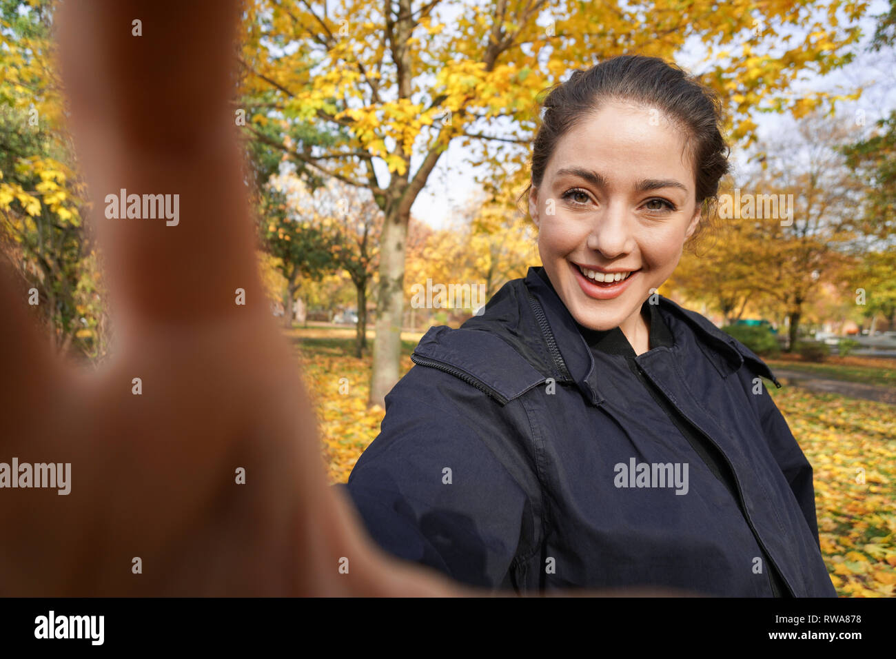 Glückliche junge Frau, die Selfie-Foto im Park mit Herbstfarben macht Stockfoto