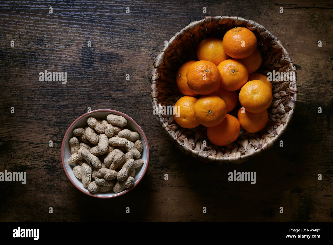 Schalen von Erdnüssen und Clementinen auf rustikalen Tisch Stockfoto