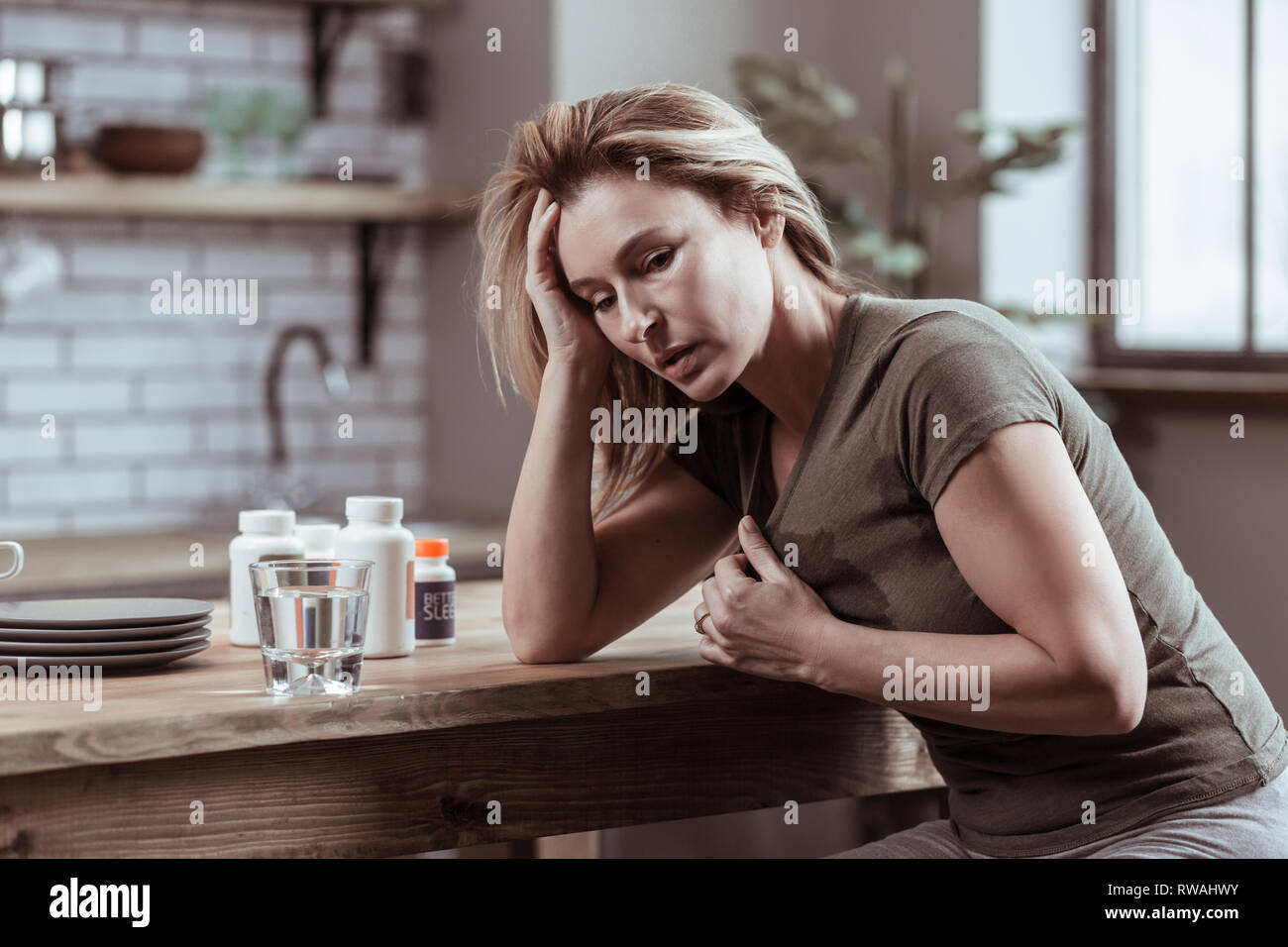 Blonde Frau mit starken Herzschmerz Tabletten Stockfoto