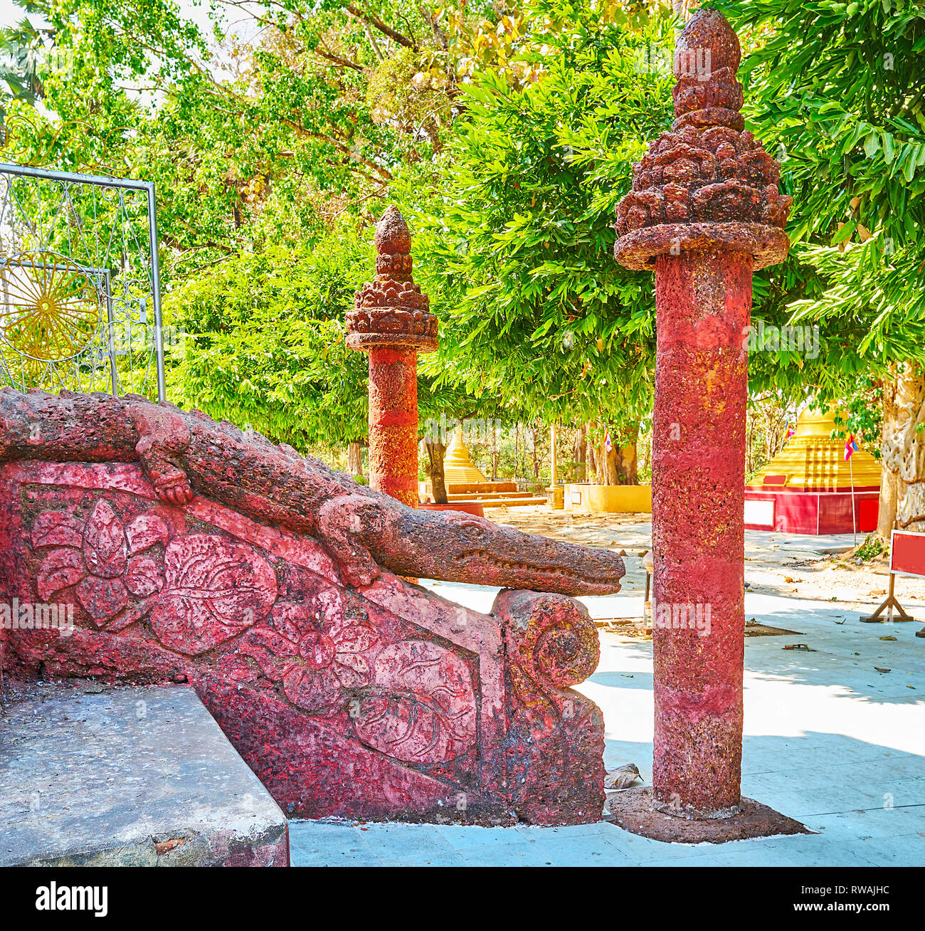 Die alten geschnitzten Geländer am Eingang des großen Stupa von Mahazedi Pagode mit Skulptur der Heiligen Krokodil und schlanken Säulen, Bago, Myanmar. Stockfoto