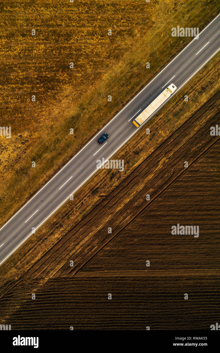 Autos und Lastwagen auf der geraden Straße durch die ebene Landschaft Landschaft, Luftaufnahme von Drone pov Stockfoto
