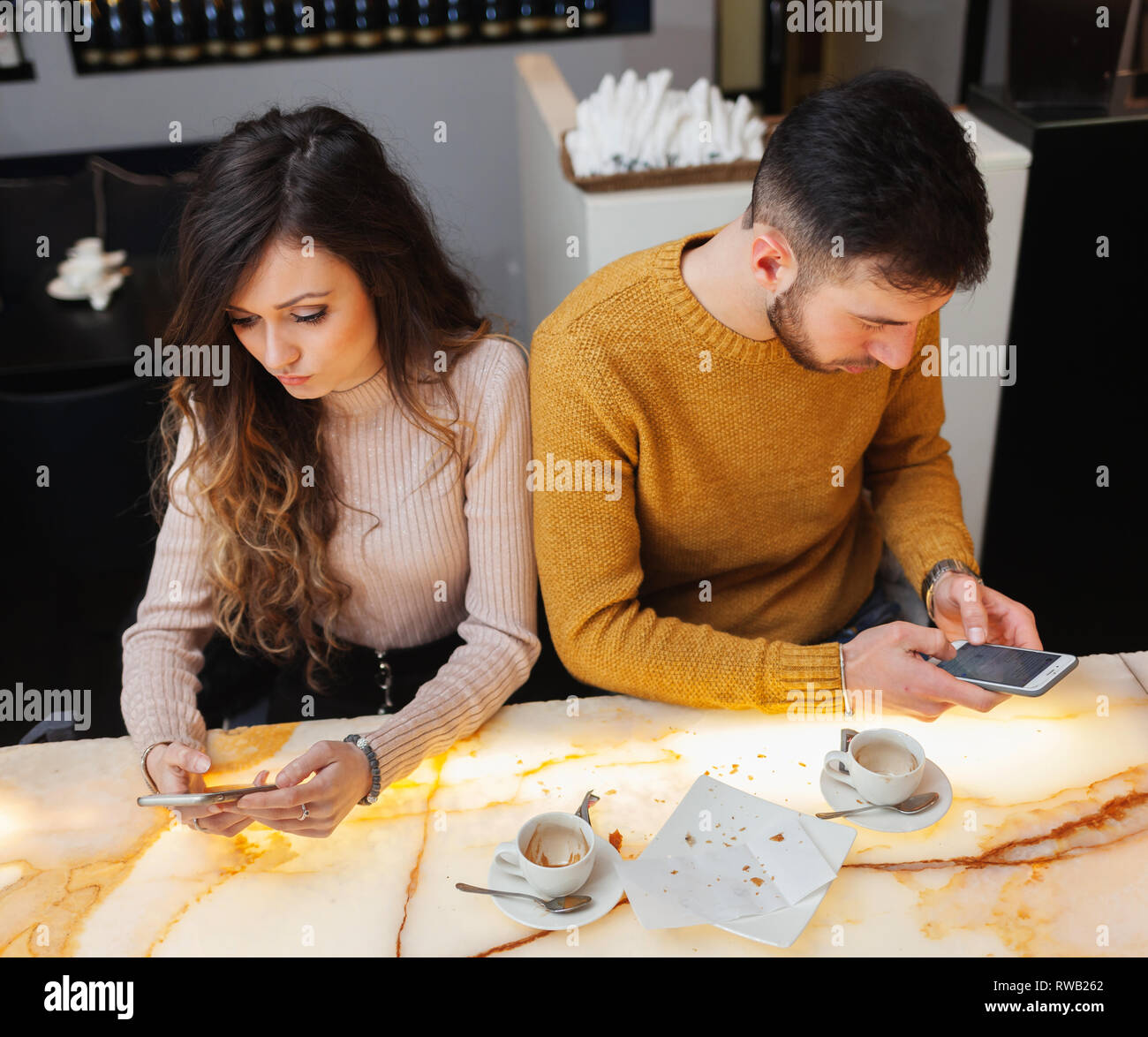 Junges Paar an der Bar und mit Handy. Soziale Netzwerke im realen Leben kann negative Auswirkungen haben. Stockfoto