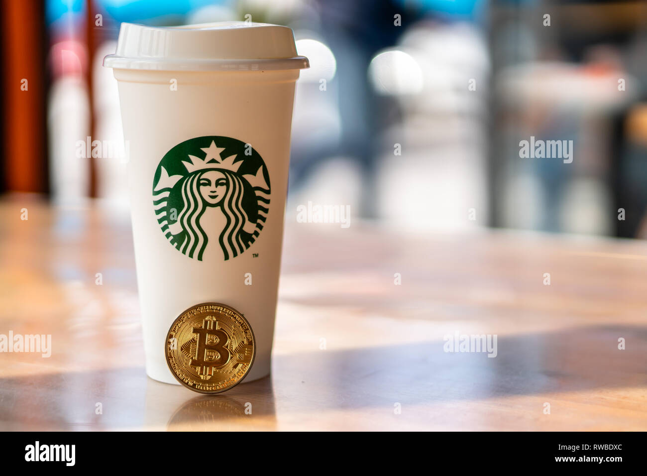 Cryptocurrency Bitcoin neben Starbucks Tasse. Starbucks Annahme des blockchain Konzept - Slowenien - 28.2.2019 Stockfoto