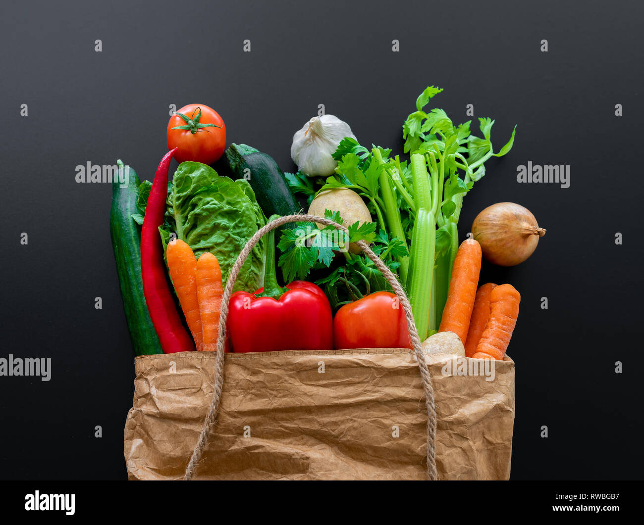 Frisches Bio-Gemüse in der braunen Papiertüte gegen dunkle Tabelle Hintergrund Stockfoto