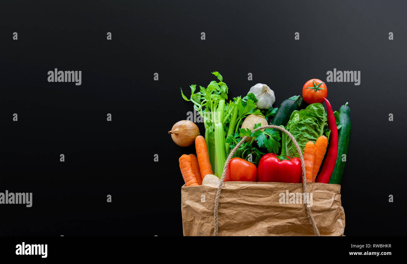 Frisches Bio-Gemüse in der braunen Papiertüte gegen dunkle Tabelle Hintergrund Stockfoto