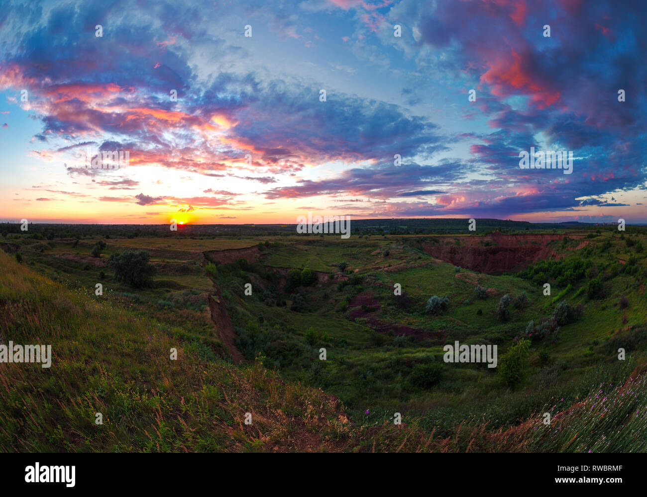 Helle Sommer bewölkter Sonnenuntergang über das grüne Tal. Abends outdoor. schöne Fotografie. Ukraine, Kriviy Rih. Ländliche weite Landschaft Stockfoto