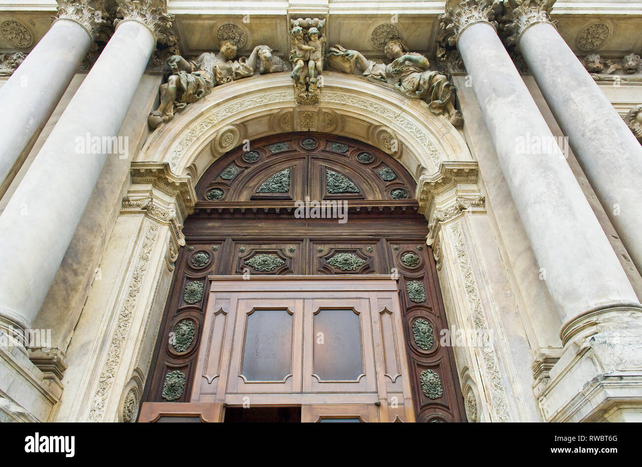 Das Äußere eines venezianischen Kirche mit Skulptur, die die Oberseite der grosse hölzerne Tür Stockfoto