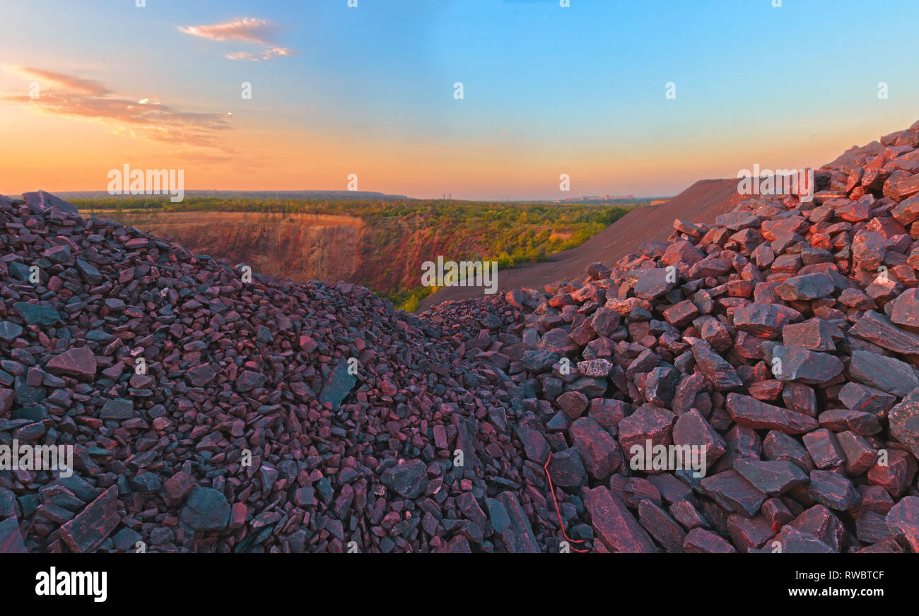 Ein dump von Eisenerz Rasse. Panoramablick auf die Landschaft von Technogenen Boden Zusammenbruch und Masse zusammenbrechen. Eine rote Steine auf Sonnenuntergang Hintergrund Stockfoto