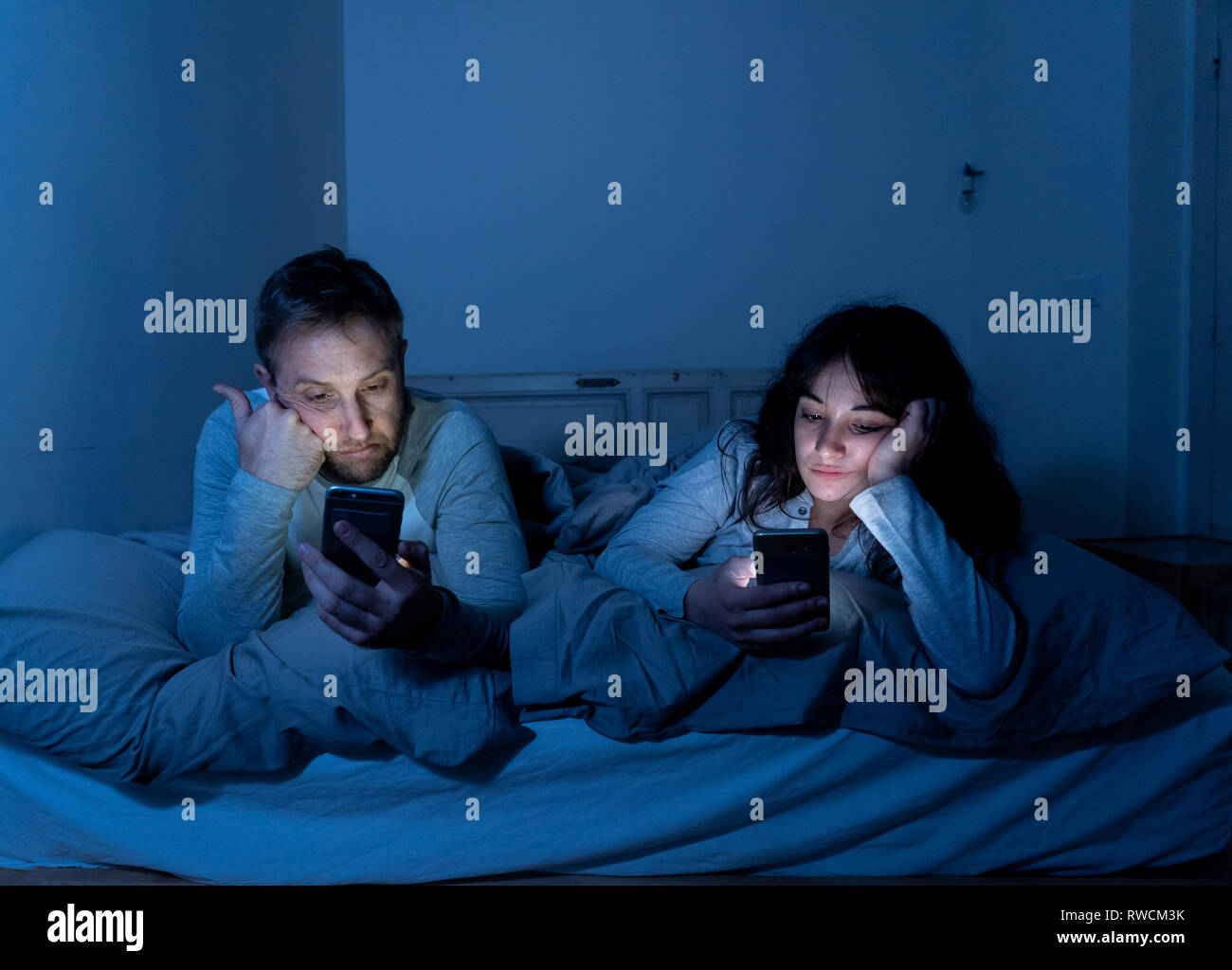 Life style Porträt der jungen gebohrt Paar nachts im Bett auf Smartphones mit Spielen, Social Media besessen, Apps gegenseitig ignorieren. Beziehung co Stockfoto