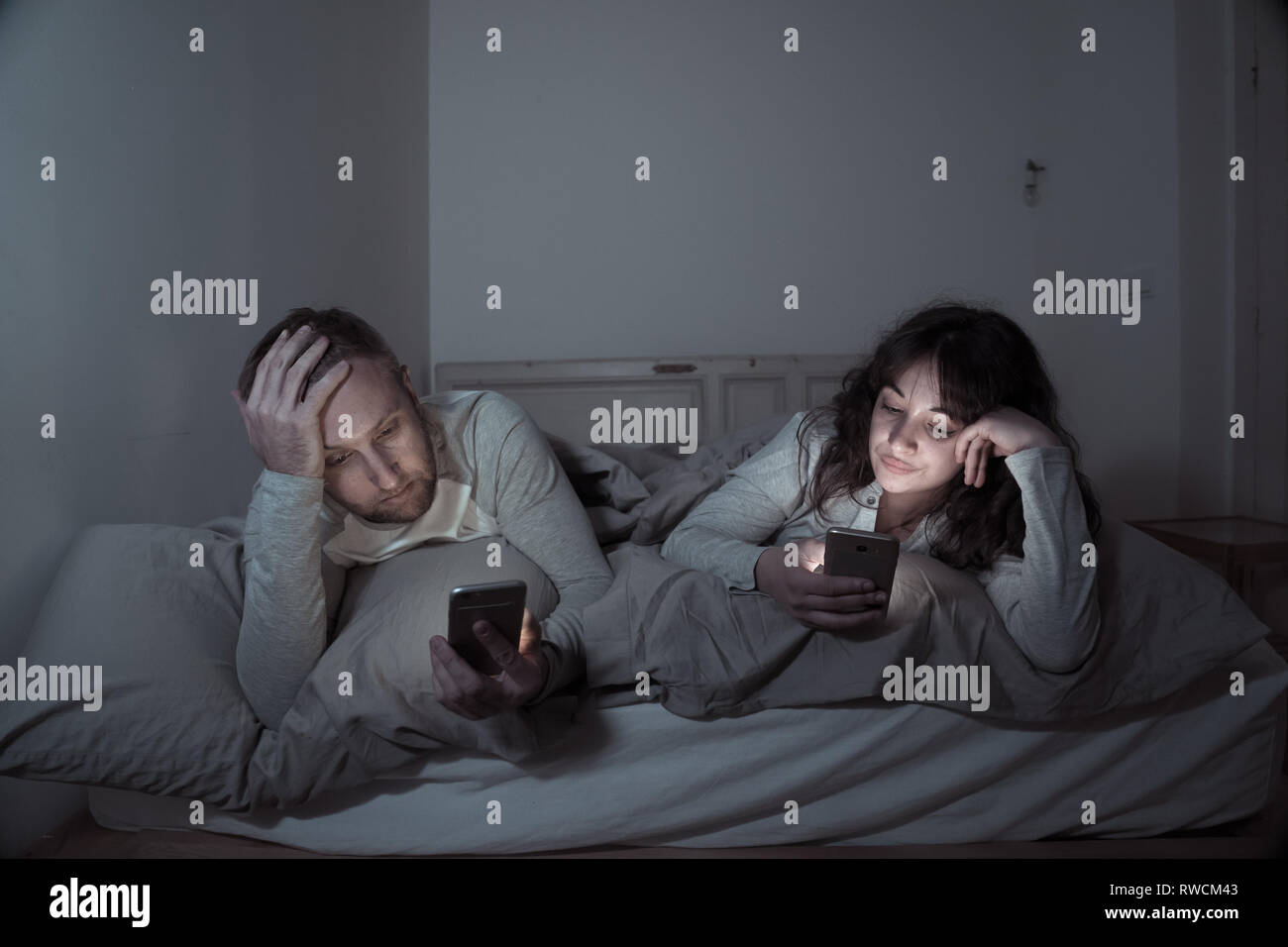 Life style Porträt der jungen gebohrt Paar nachts im Bett auf Smartphones mit Spielen, Social Media besessen, Apps gegenseitig ignorieren. Beziehung co Stockfoto