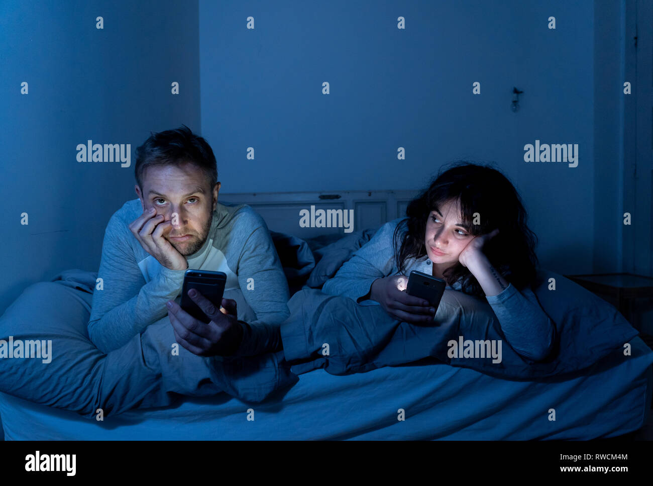 Life style Porträt der jungen gebohrt Paar nachts im Bett auf Smartphones mit Spielen, Social Media besessen, Apps gegenseitig ignorieren. Beziehung co Stockfoto