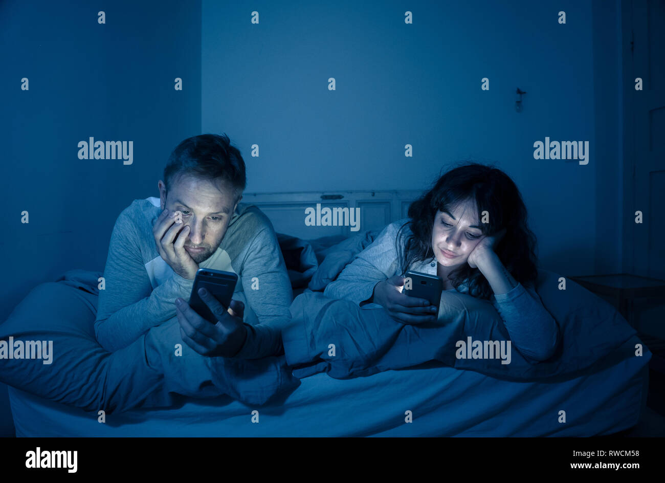 Life style Porträt der jungen gebohrt Paar nachts im Bett auf Smartphones mit Spielen, Social Media besessen, Apps gegenseitig ignorieren. Beziehung co Stockfoto