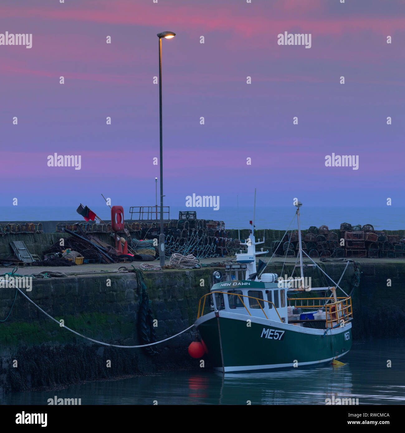 Das Fischerboot 'New Dawn' sitzt auf seinem Liegeplatz unter einer Straßenlaterne als Dawn kommt an Gourdon auf der Aberdeenshire Küste Stockfoto