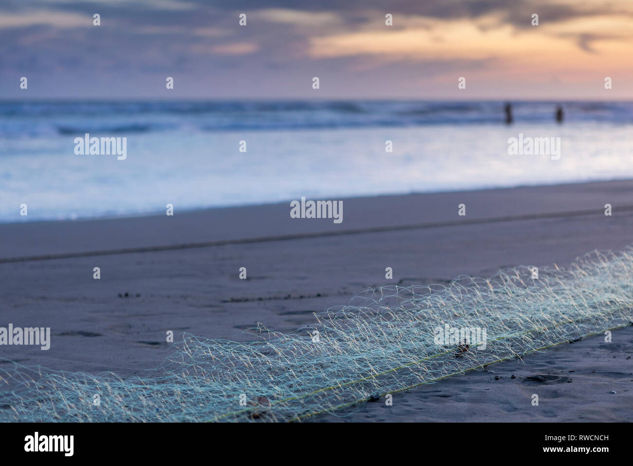 Fischernetz an einem Sandstrand der Mexikanischen Strand mit drei Leute im Wasser im Hintergrund stehend Stockfoto