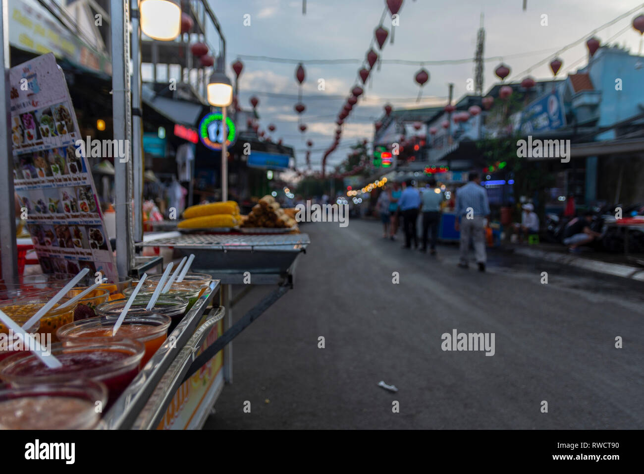 Schalen mit unterschiedlichen Marmelade und streetfood im Vordergrund und Nachtmarkt in Duong Dong Stadt Insel Phu Quoc Vietnam im Hintergrund. Stockfoto