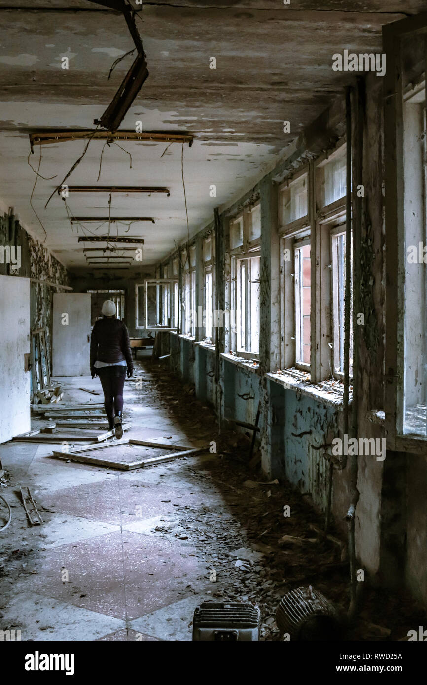 Frau geht durch die verlassenen Gänge einer Schule innerhalb der Sperrzone von Tschernobyl Stockfoto