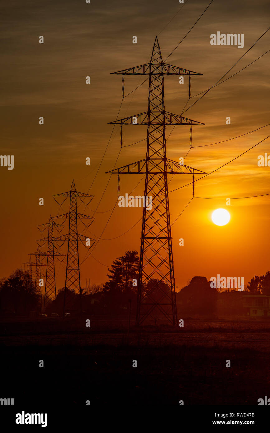 Hochspannungsmasten gegen das Licht bei Sonnenuntergang Stockfoto